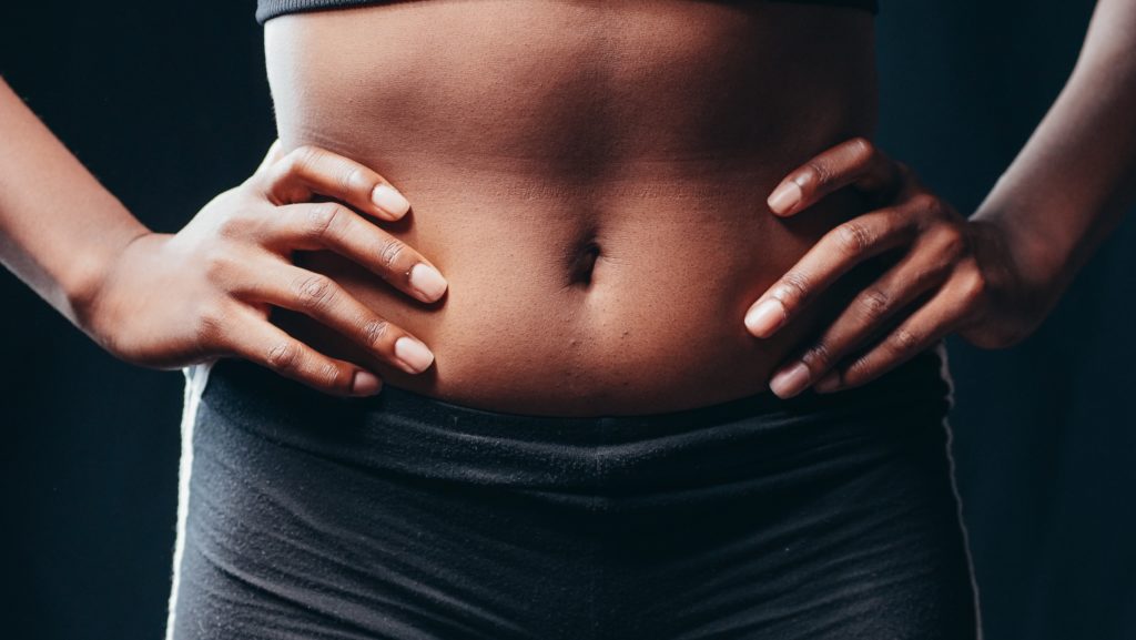 a closeup of a woman's stomach with her hands on her hips